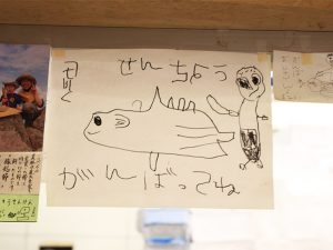 子供たちから“船長”のニックネームで呼ばれている森田さん。写真の絵は、鰹節の一大産地・鹿児島県枕崎市の友人の子からプレゼントされた、ライブ中に魚の解体をする“船長”の図。