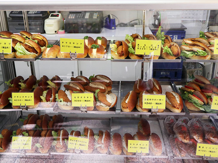 右のガラスケースには20種類以上の「おかずパン」、左にはクリームパンやアンパンなどの「おやつパン」がずらりと並ぶ