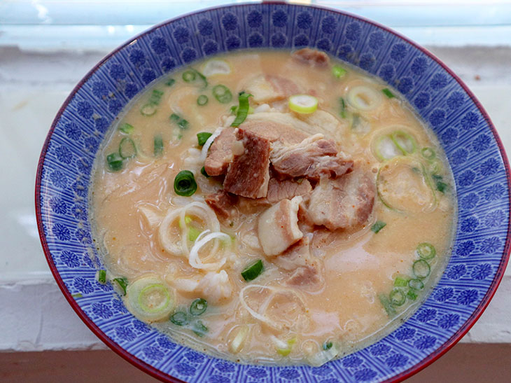 「テジクッパ」。豚肉ベースの白濁スープに、ネギとコチュジャン、豚肉が入っています。豚肉はとても柔らかく煮込まれていて、その濃厚な味がスープに溶け出しており、甘みもあります