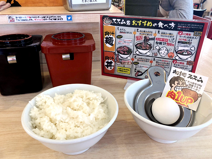 「白飯」100円。黒と赤の入れ物には紅生姜、キュウリの漬物が入っています