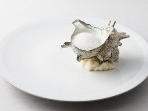 「貝類とハーブ」（リオネル）一見、シンプルなサザエの料理のようでいて、殻の中には、白いかや貝類、様々なハーフがつかわれている