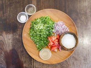 「水菜と紫玉ねぎのサンボーラ」の材料。お皿の上は、水菜、紫玉ネギ、トマト、ココナッツフィン、レモン汁。調味料は塩とブラックペッパー