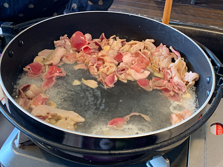 すき焼き鍋のような鉄鍋で、にんにく、豚バラ肉、鶏肉、砂肝を炒める。この香りだけで食欲をそそる