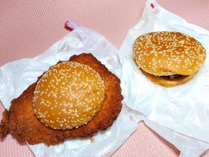 「ジーパイバーガー」と「甘辛チキンバーガー」の比較。ジーパイのワイドな大きさは見ての通り。実測値は約16cm×約12.5cm×厚さ約8mm
