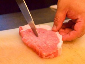ロース肉にはしっかり筋切りをして縮まないように。揚げる前の肉で結構厚めなので、衣をつけるとさらに厚みが（食楽web）