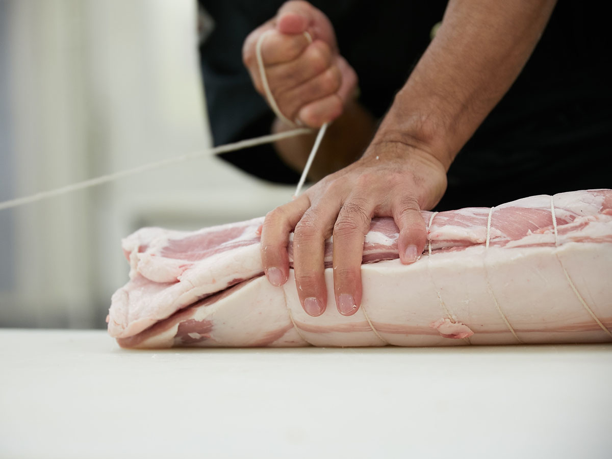 紅豚の肉塊をまるめるように水糸で縛っていく。この縛り方ひとつで焼き上がりも変わる