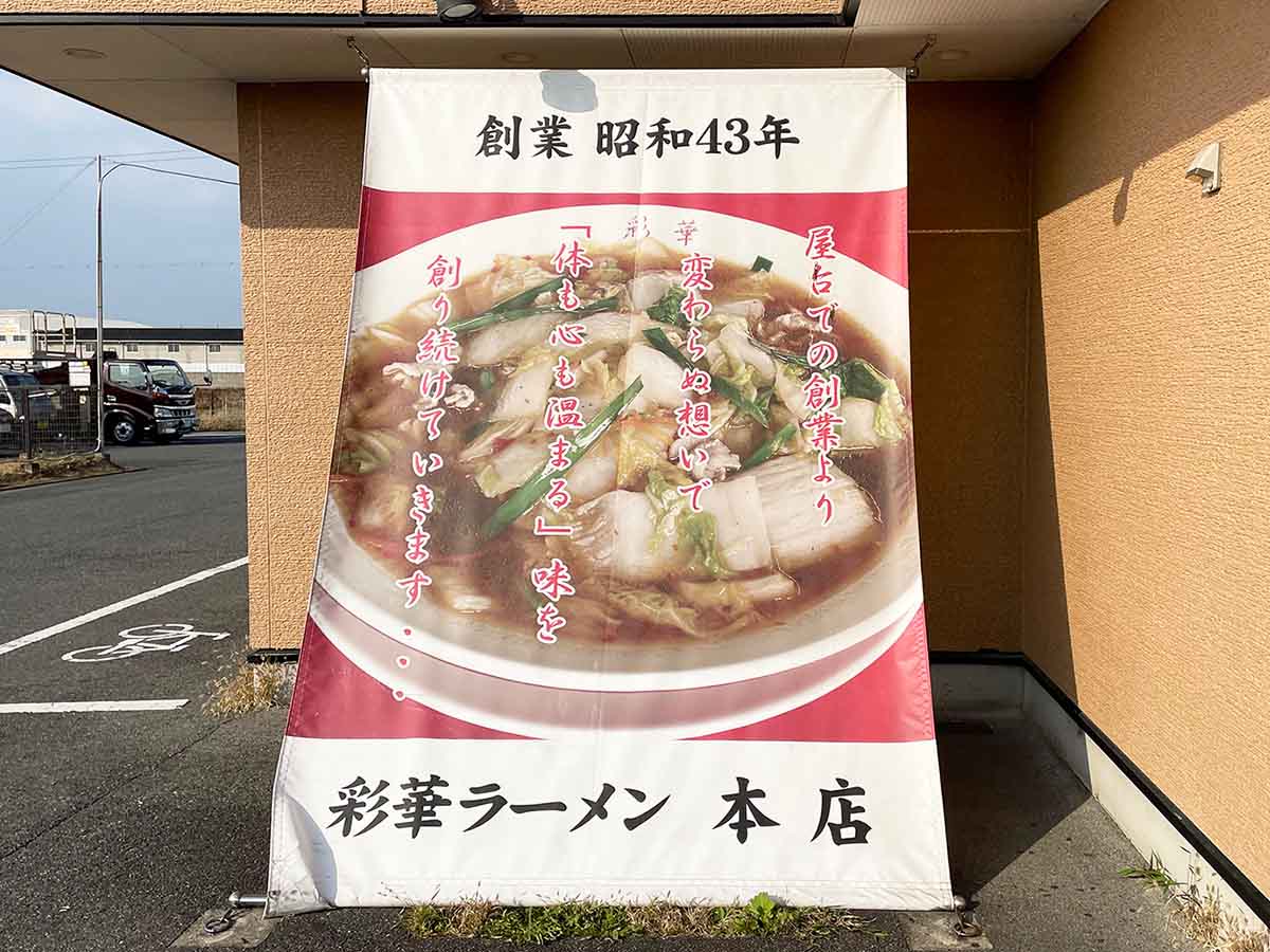 奈良県天理市にある『彩華ラーメン（本店）』の入口には、デカデカと掲げられた「サイカラーメン」の写真が