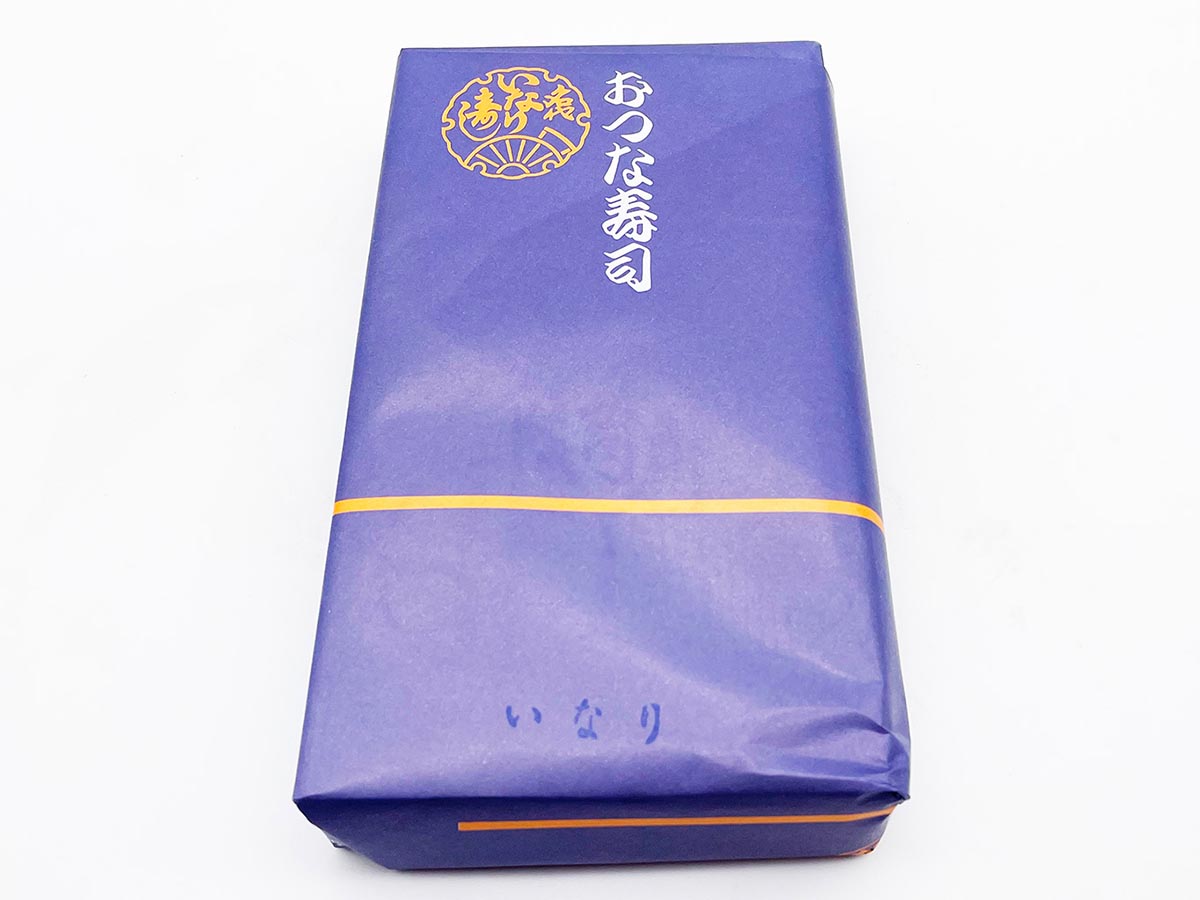 『おつな寿司』の「いなり寿司」1160円（税込）。濃紺にオレンジのラインの包装紙。高級感があります