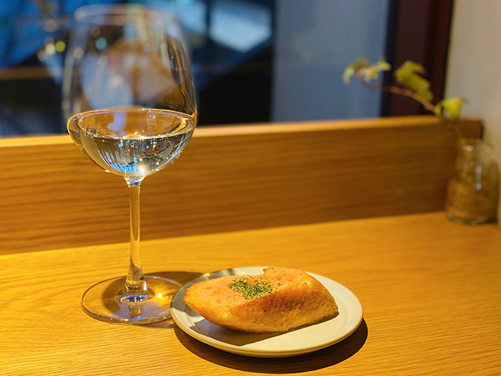 「グラスワイン」600円～ （税込） 「明太トースト」付き。日本各地のご当地ワインから店主が「パンに合うワイン」をセレクトしている