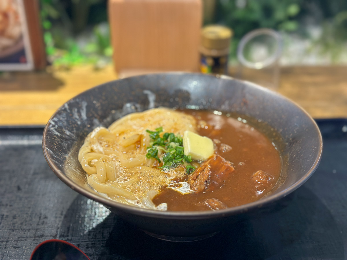 「カレボナーラうどん」（990円）は、生卵を絡めたカルボナーラのようなうどんに、牛すじカレーがかかった一品