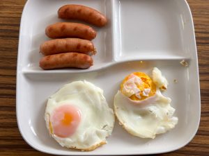 できあがった目玉焼きとソーセージ。崩れてしまったのは油を敷かなかったせい