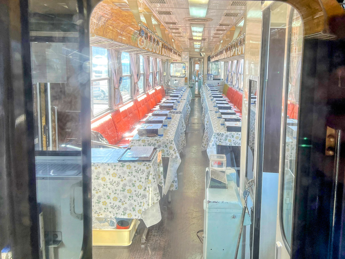 食堂車は4人掛けテーブルがずらりと並ぶイメージがありましたが、きのこ列車の場合は、一般的なロングシートの前に机を並べる仕様。見知らぬ旅客と顔をつき合わせて食べるのも面白い