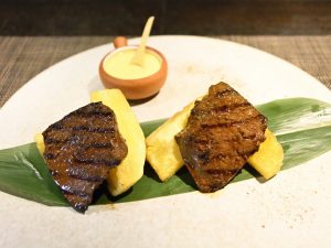 「牛ハツのアンティクーチョ」 下に敷いてあるのはキャッサバ芋のフライ、奥にあるのはアヒ・アマリージョという黄色の唐辛子のソース