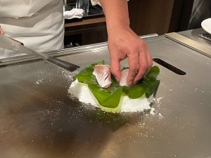 鉄板の上に塩を山盛りにし、野菜ともみじ鯛をのせる