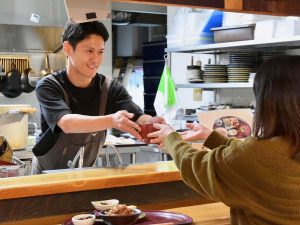 厨房担当の1人、上田辰也さん。ランチはカウンターで受け取るセルフサービス。プラス料金で汁物や主菜、物販で扱うジュースなどの追加もできます