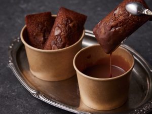 チョコレートにディップしているフィナンシェ