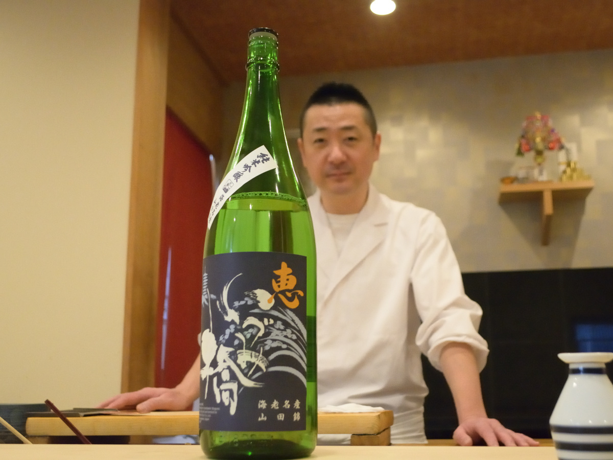 「いづみ橋 恵 青ラベル 純米吟醸」(泉橋酒造株式会社)と遠藤さん。泉橋酒造株式会社のモットーは“酒造りは米作りから”