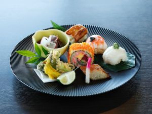 下段：（手前より時計回りに）「稚鮎と旬野菜の天婦羅」、「蛍烏賊の胡麻味噌掛け」、「手毬寿司3種」、「カリフォルニアロール」、「銀鱈西京焼き」