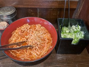 卓上に置いてあるもやしナムルは食べ放題。ビールのつまみにも相性良し。また、ネギも食べ放題