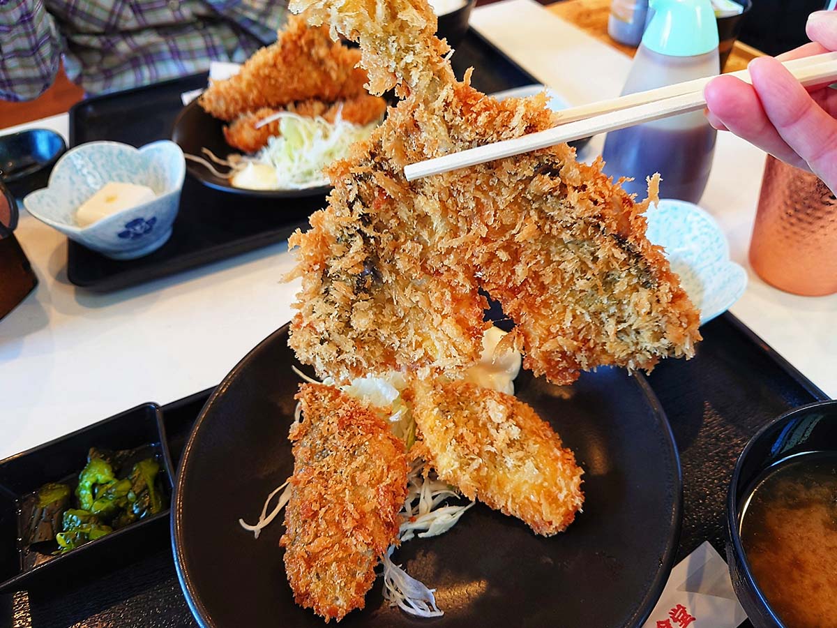 大きな黄金アジフライの下から他のフライが出てくる [食楽web]