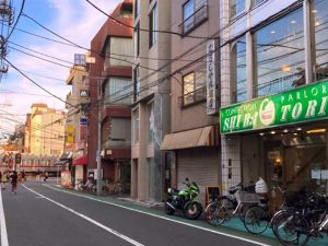 路面電車を望む『白鳥』の店先と街並み