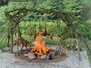 肉汁が焼け石や薪に滴り落ち、香ばしい香りが漂う