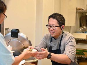 優しい笑みを湛えて配膳する『Restaurant タナカ』の田中シェフ
