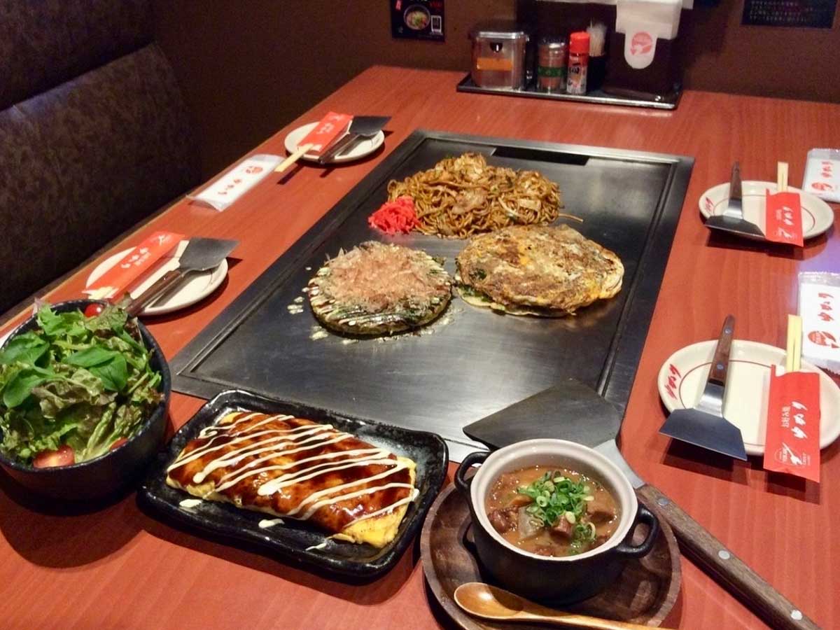 鉄板の上で焼き上がるお好み焼きと焼きそば。香ばしさが食欲をそそる [食楽web]