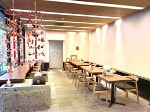 天然のオーク1枚板のテーブルと窓ガラスから差し込む太陽があたたかい雰囲気の店内